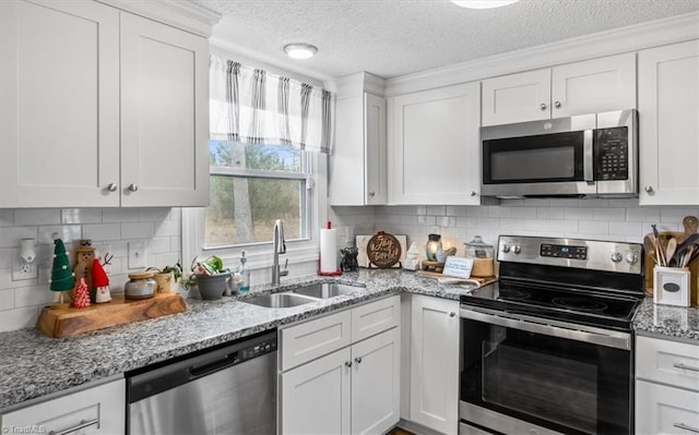 kitchen with sink, a textured ceiling, light stone counters, white cabinetry, and stainless steel appliances