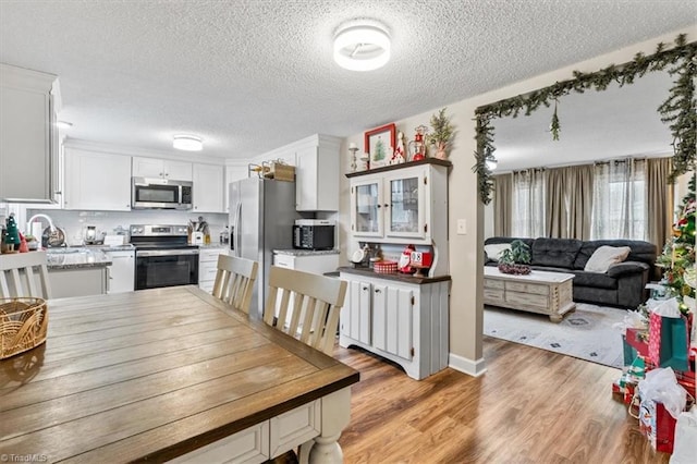 dining space with sink, light wood-type flooring, and a textured ceiling