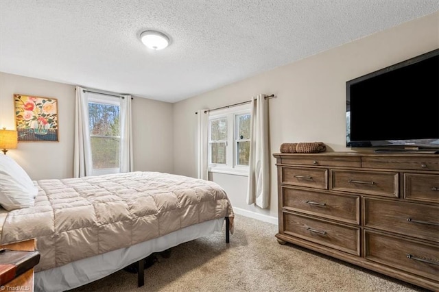 bedroom with a textured ceiling, light colored carpet, and multiple windows