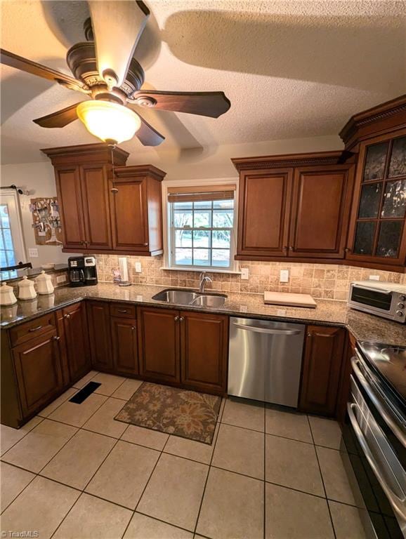 kitchen with light tile patterned flooring, ceiling fan, tasteful backsplash, sink, and stainless steel appliances