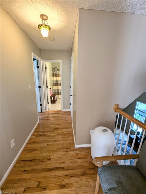 hallway featuring light wood-type flooring and a textured ceiling