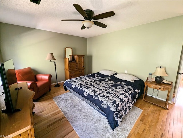 bedroom with light wood-type flooring, ceiling fan, and a textured ceiling