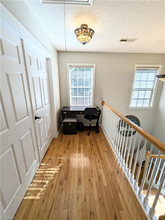 hall featuring a textured ceiling and light hardwood / wood-style flooring