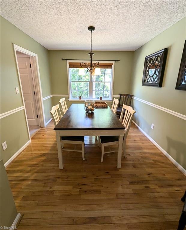 dining space with a notable chandelier, hardwood / wood-style floors, and a textured ceiling