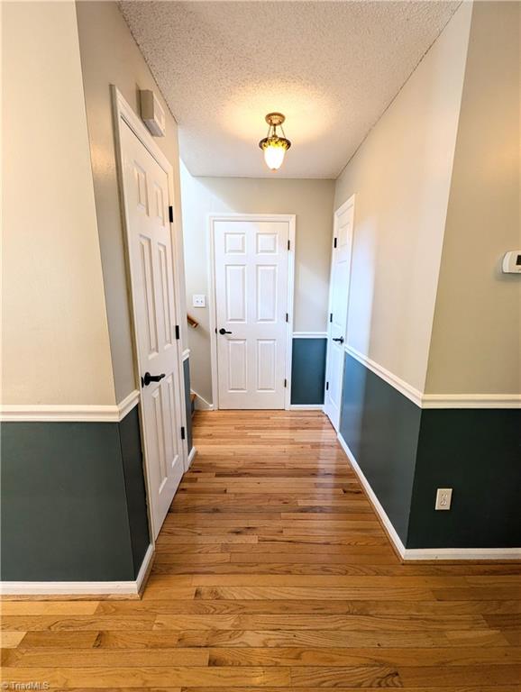 hallway with a textured ceiling and light wood-type flooring