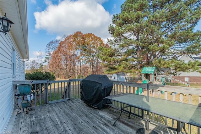 wooden deck featuring a playground and area for grilling