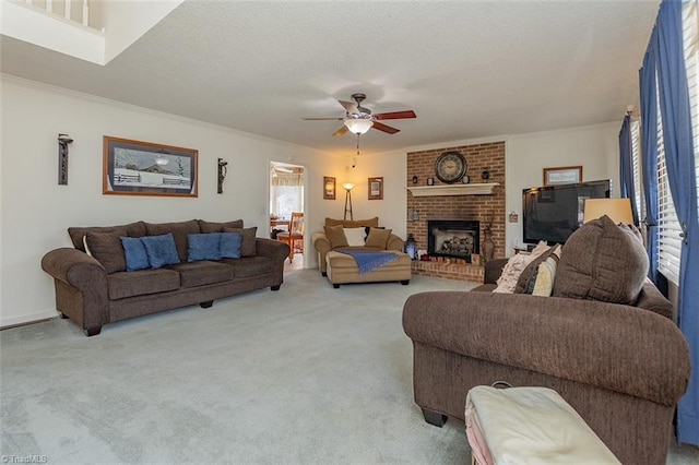 carpeted living room with ceiling fan, a fireplace, crown molding, and a textured ceiling