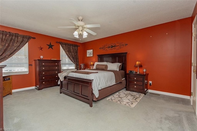 bedroom featuring ceiling fan, light colored carpet, a textured ceiling, and multiple windows