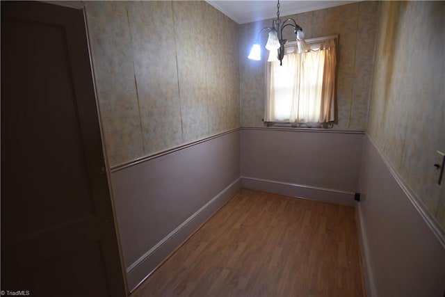 empty room with ornamental molding, a chandelier, and wood-type flooring