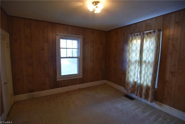 unfurnished room featuring a textured ceiling and wooden walls