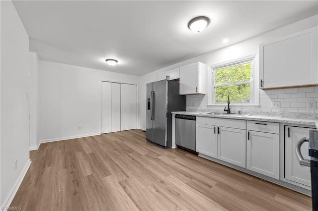 kitchen with stainless steel appliances, backsplash, a sink, and light wood-style floors
