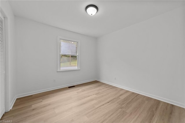 spare room featuring baseboards, visible vents, and light wood-style flooring