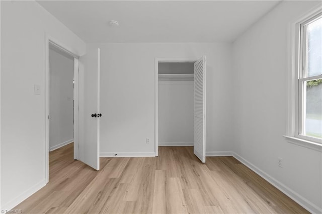 unfurnished bedroom featuring light wood-style flooring, a closet, and baseboards