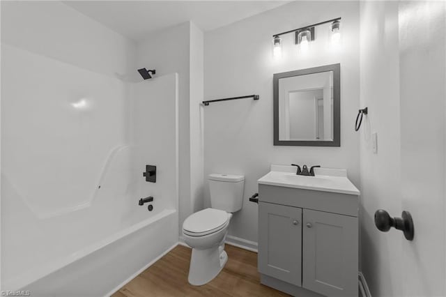 bathroom with wood finished floors, shower / bath combination, toilet, vanity, and baseboards