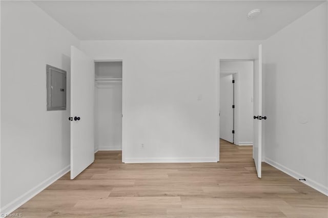 unfurnished bedroom with electric panel, light wood-style flooring, and baseboards
