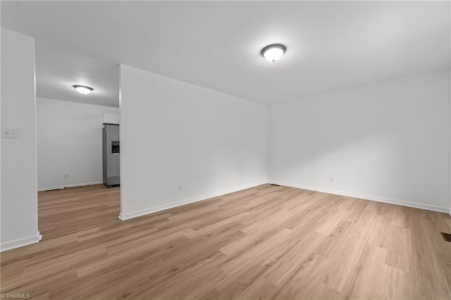 empty room featuring baseboards and light wood finished floors