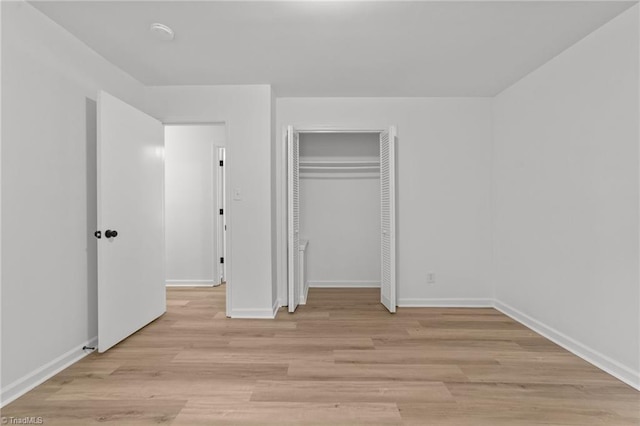 unfurnished bedroom featuring baseboards, light wood finished floors, and a closet