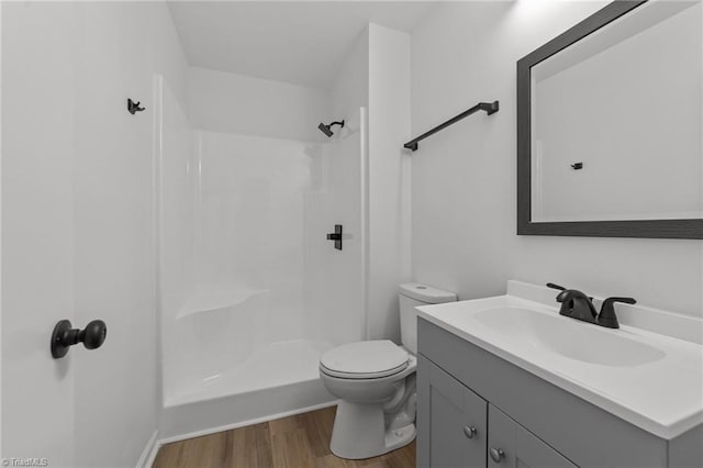 full bath featuring walk in shower, wood finished floors, vanity, and toilet