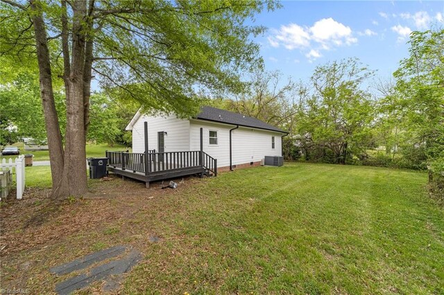 rear view of property with central air condition unit, a lawn, a shingled roof, and a deck