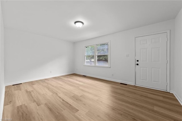 empty room featuring baseboards, wood finished floors, and visible vents