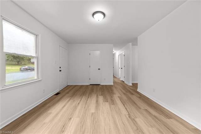 unfurnished room with baseboards, visible vents, and light wood finished floors