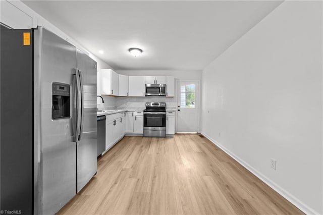 kitchen with a sink, light countertops, stainless steel appliances, light wood-style flooring, and white cabinetry