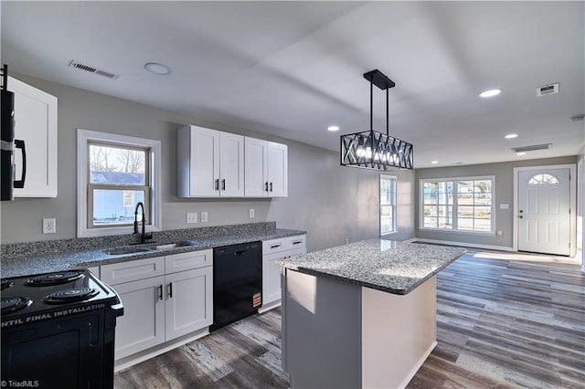 kitchen with black appliances, dark wood finished floors, a sink, and visible vents