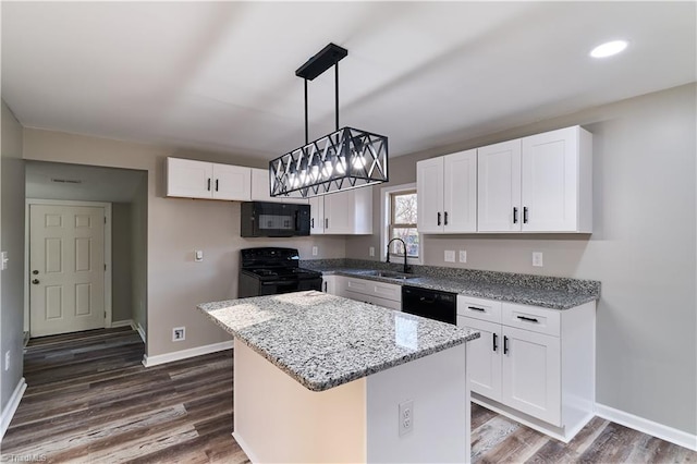 kitchen featuring white cabinets, a kitchen island, light stone counters, black appliances, and a sink