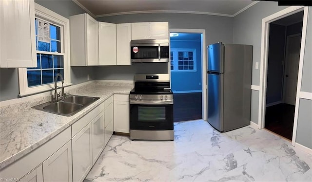 kitchen featuring light stone countertops, ornamental molding, stainless steel appliances, sink, and white cabinets