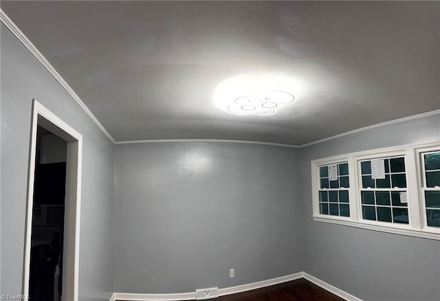 spare room with crown molding and dark wood-type flooring