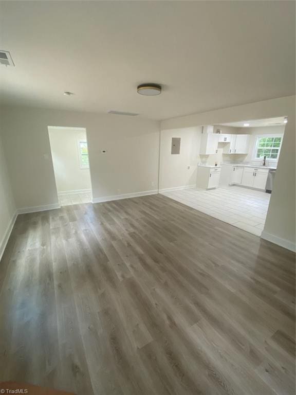 820 Broad Ave, Greensboro, NC 27406 - unfurnished living room with visible vents, a sink, baseboards, and wood finished floors