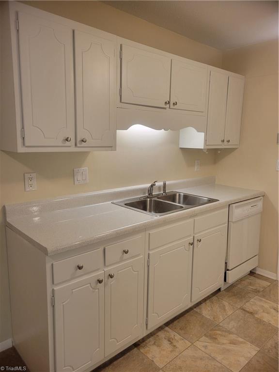 kitchen featuring baseboards, a sink, white cabinetry, and dishwasher