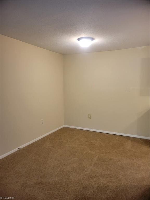 carpeted spare room featuring baseboards and a textured ceiling