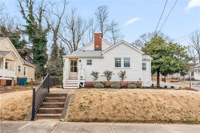 bungalow with a shingled roof and a chimney