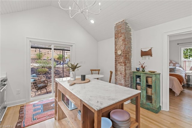 dining area featuring a chandelier, light wood-type flooring, and lofted ceiling