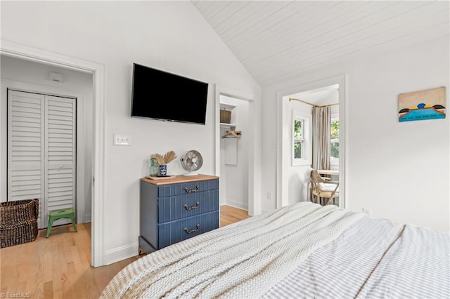 bedroom with light wood-type flooring, vaulted ceiling, and baseboards