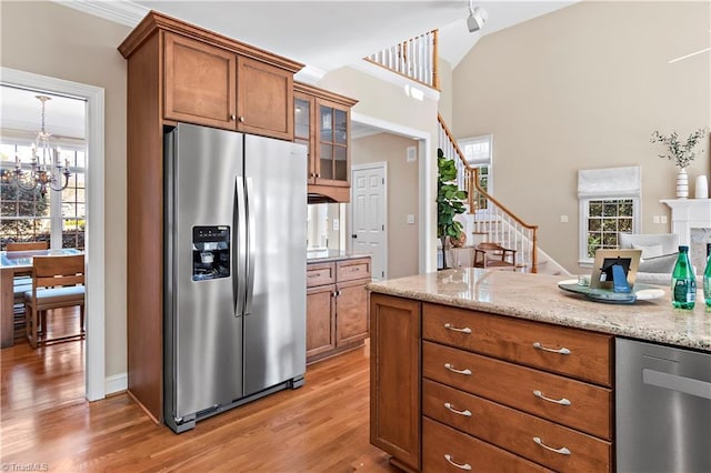 kitchen with stainless steel refrigerator with ice dispenser, a healthy amount of sunlight, an inviting chandelier, and light hardwood / wood-style flooring