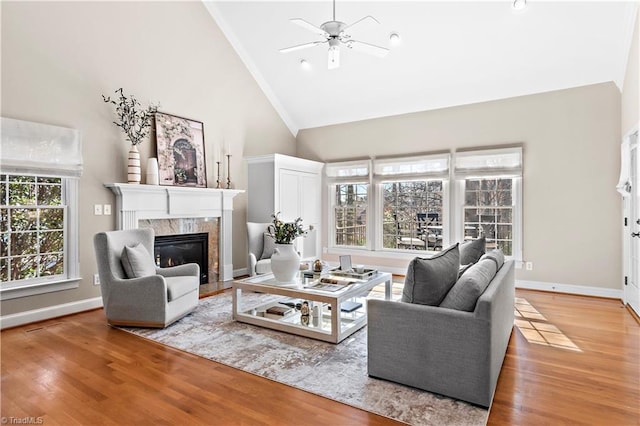 living room with ceiling fan, high vaulted ceiling, a premium fireplace, and hardwood / wood-style floors