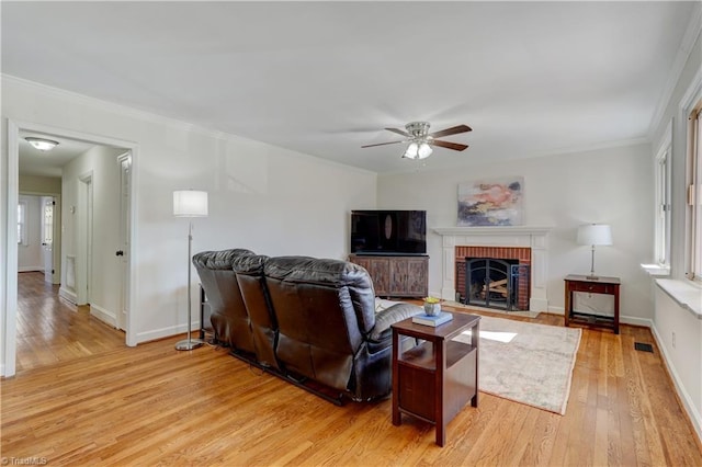 living room featuring crown molding, a fireplace, and light wood-type flooring