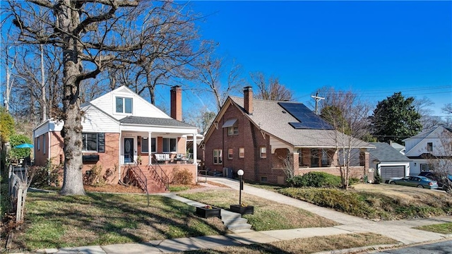 bungalow-style home with a porch, a front yard, and solar panels