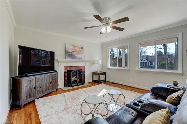 living room featuring a brick fireplace, ornamental molding, ceiling fan, and light wood-type flooring