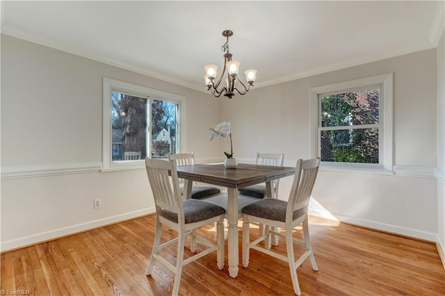 dining room featuring a notable chandelier, a wealth of natural light, light hardwood / wood-style flooring, and ornamental molding