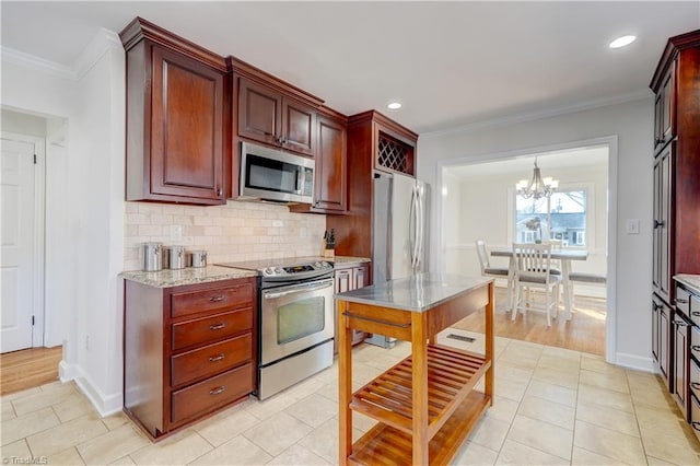 kitchen featuring crown molding, tasteful backsplash, appliances with stainless steel finishes, pendant lighting, and light stone countertops