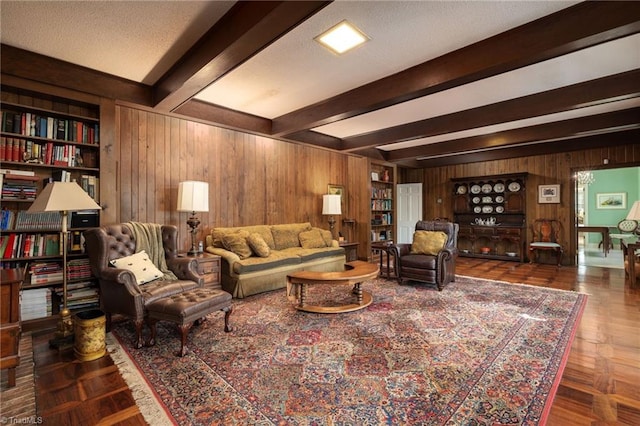 living room featuring built in features, wood walls, a textured ceiling, and beam ceiling