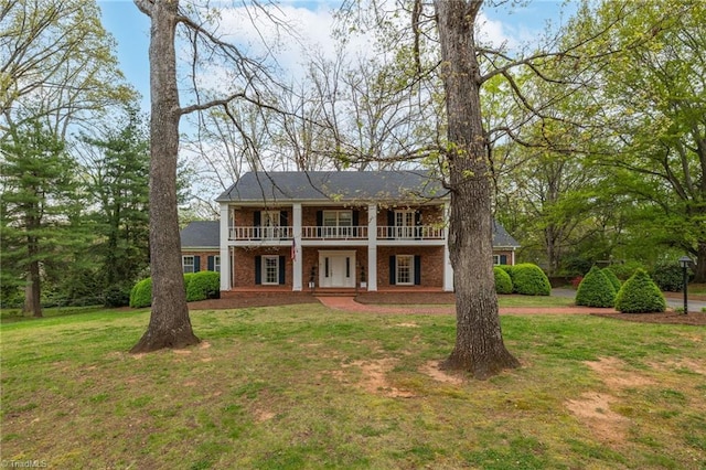 view of front of property with a front yard, a balcony, and a patio area