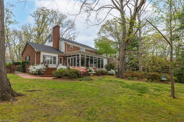 rear view of house with a sunroom and a yard