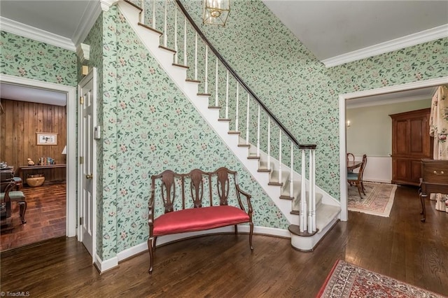 staircase with an inviting chandelier, wood walls, ornamental molding, and dark hardwood / wood-style floors