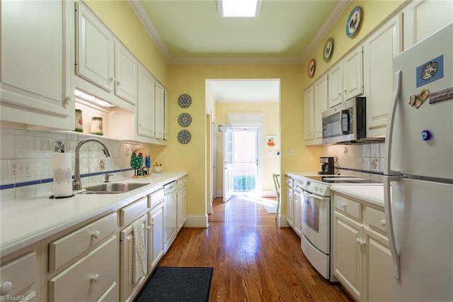 kitchen with white appliances, white cabinets, sink, ornamental molding, and dark hardwood / wood-style flooring