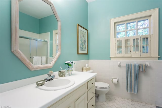 bathroom with an enclosed shower, vanity, tile walls, tile patterned flooring, and toilet