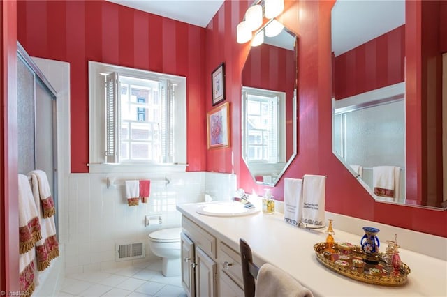 bathroom with walk in shower, vanity, tile walls, tile patterned flooring, and toilet